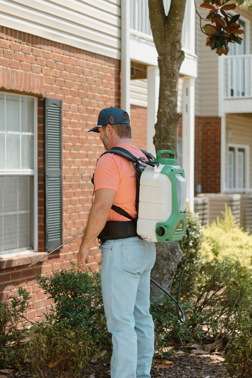 Cole's Pest Control technician treating a home exterior in Bossier City